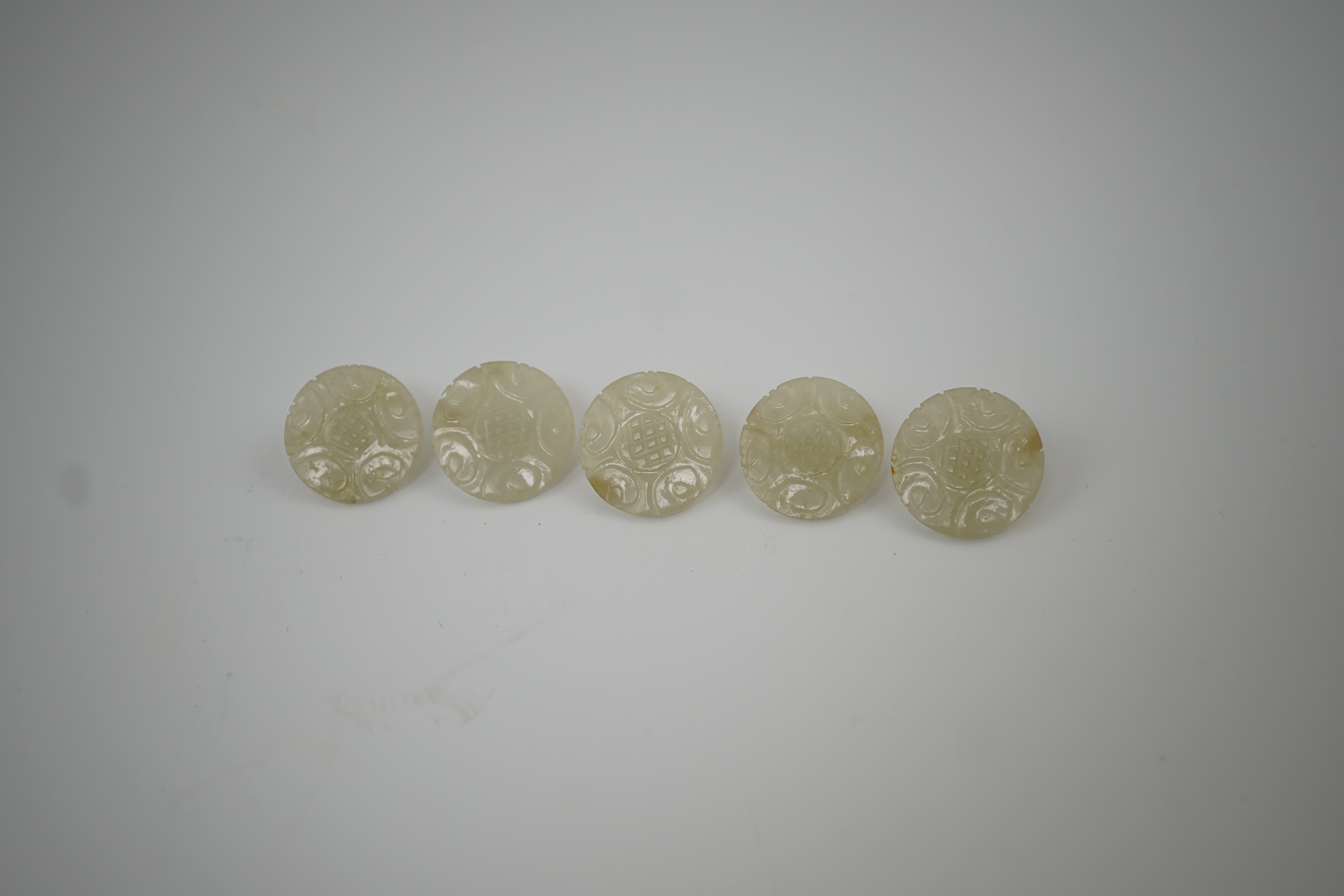 A set of five Chinese pale celadon jade robe buttons, 19th century